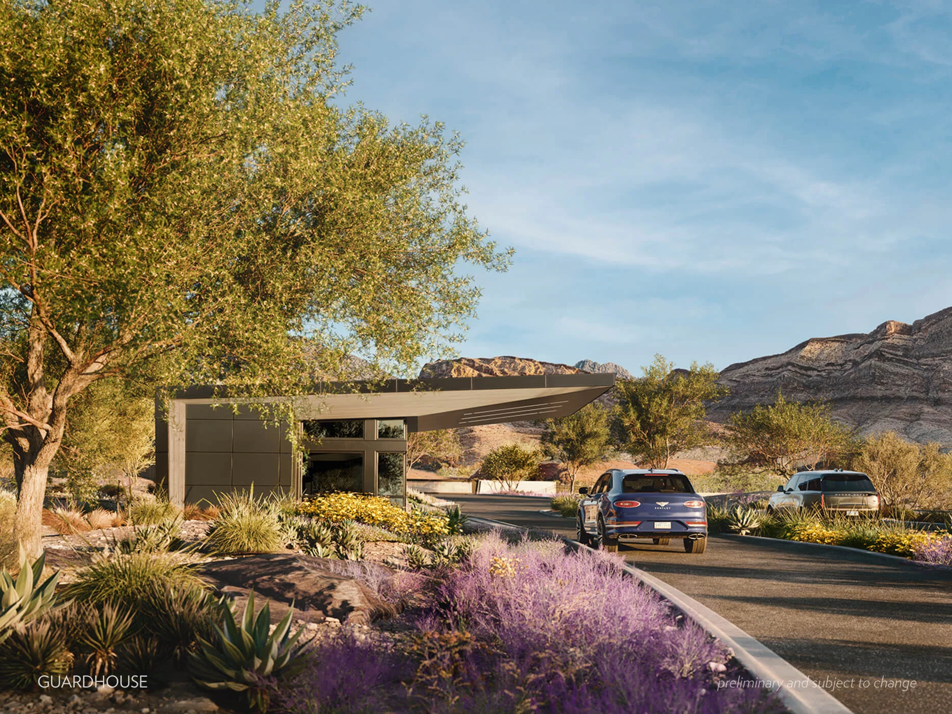 Guardhouse_w_caption_@1x A modern custom guardhouse sits beside a landscaped driveway in a southern Nevada desert setting, with two cars approaching and mountains visible in the background under a clear blue sky.